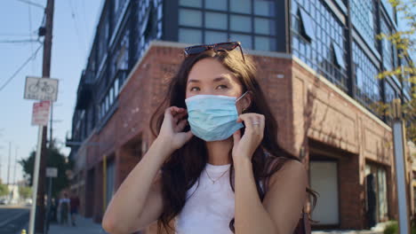 pretty girl putting mask on street. attractive asian woman use face protection