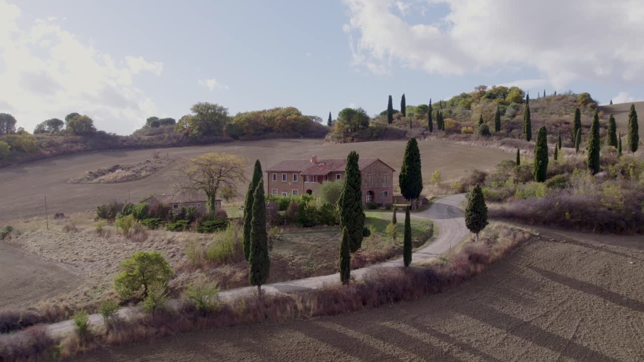 Dolci colline e villa di campagna con alberi iconici, Toscana, Italia.