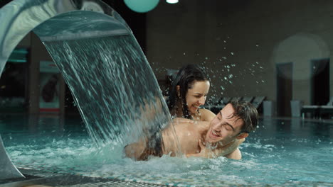 cheerful couple laughing in spa pool. happy man and woman having fun in jacuzzi