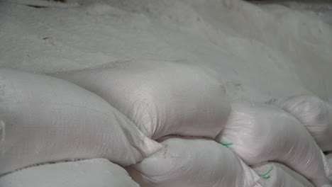 sacks of raw organic sea salt stacked inside farm barn - close-up