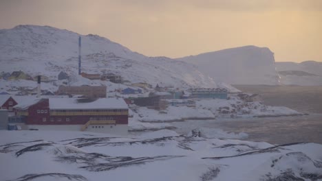 Cámara-Lenta-De-La-Ciudad-Costera-De-Ilulissat,-Groenlandia-Al-Atardecer-En-Invierno-Con-Glaciares-E-Icebergs-En-El-Fondo