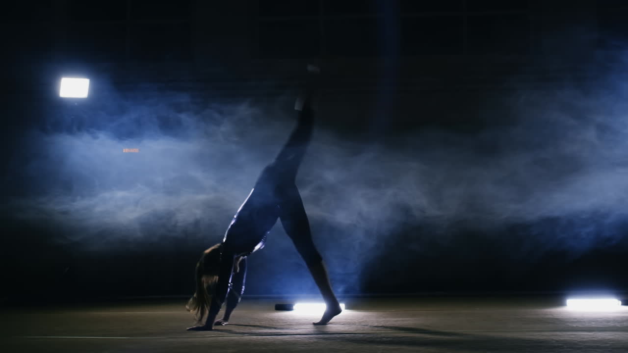 Girl gymnast performs a somersault on a gym Mat in slow motion.