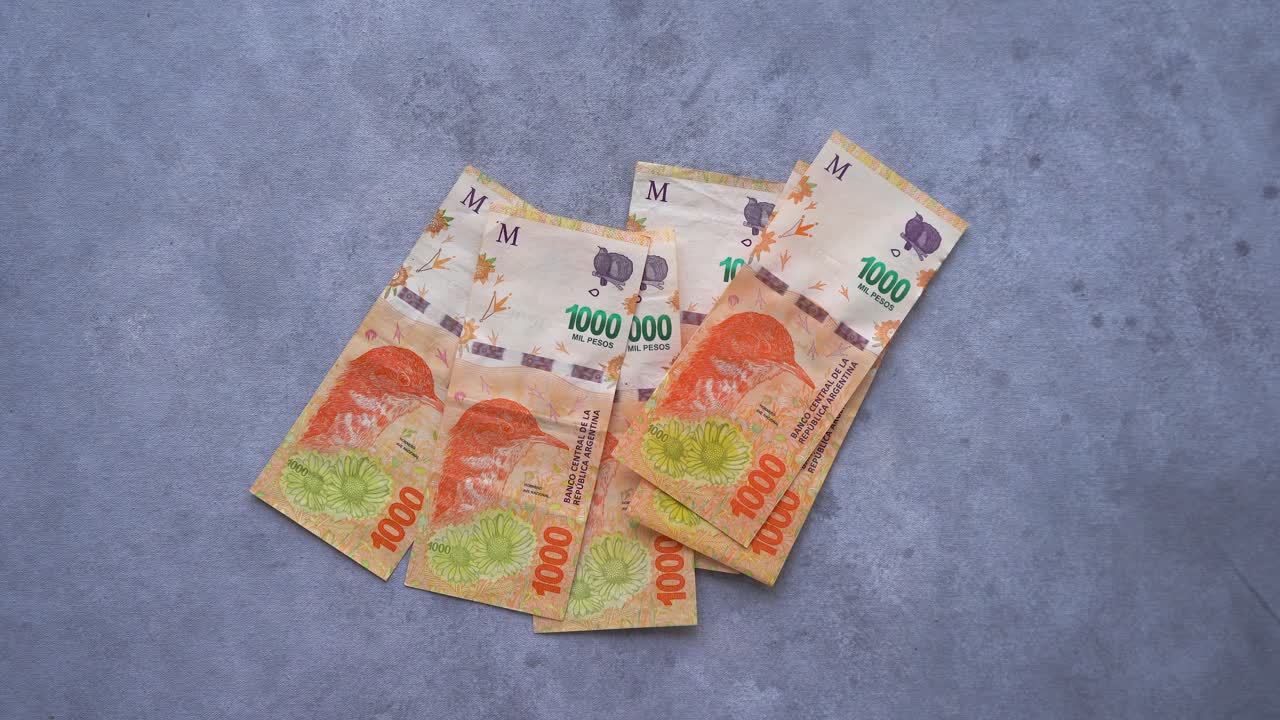 많은 $1000 아르헨티나 페소 지폐를 하나씩 테이블에 던지는 손