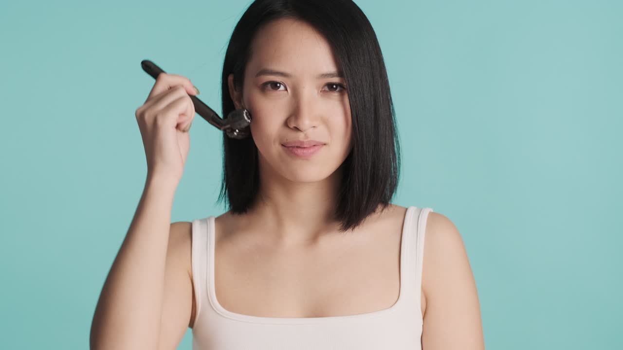 una mujer asiática masajeando su cara.