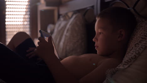 Child-lying-in-bed-and-watching-cartoon-on-tablet-computer