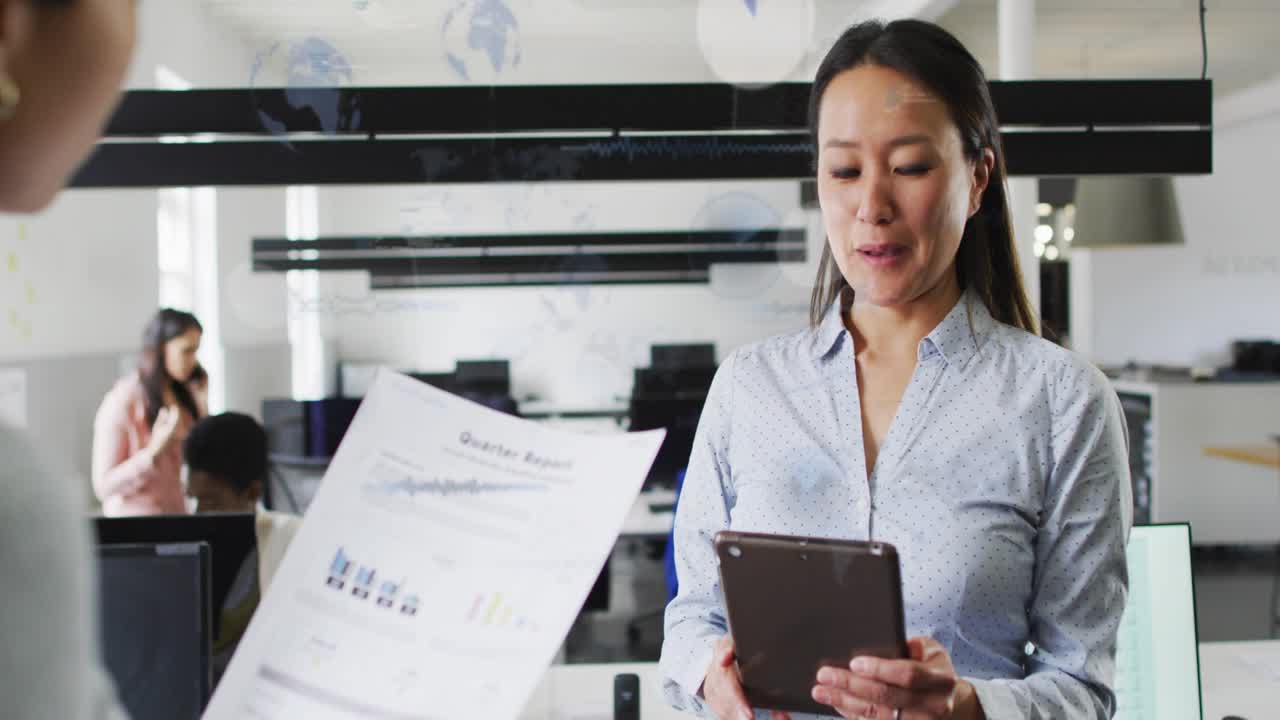 PM reading tablet while peer showing Qtr Report, blue data covering faces, charts during biz review