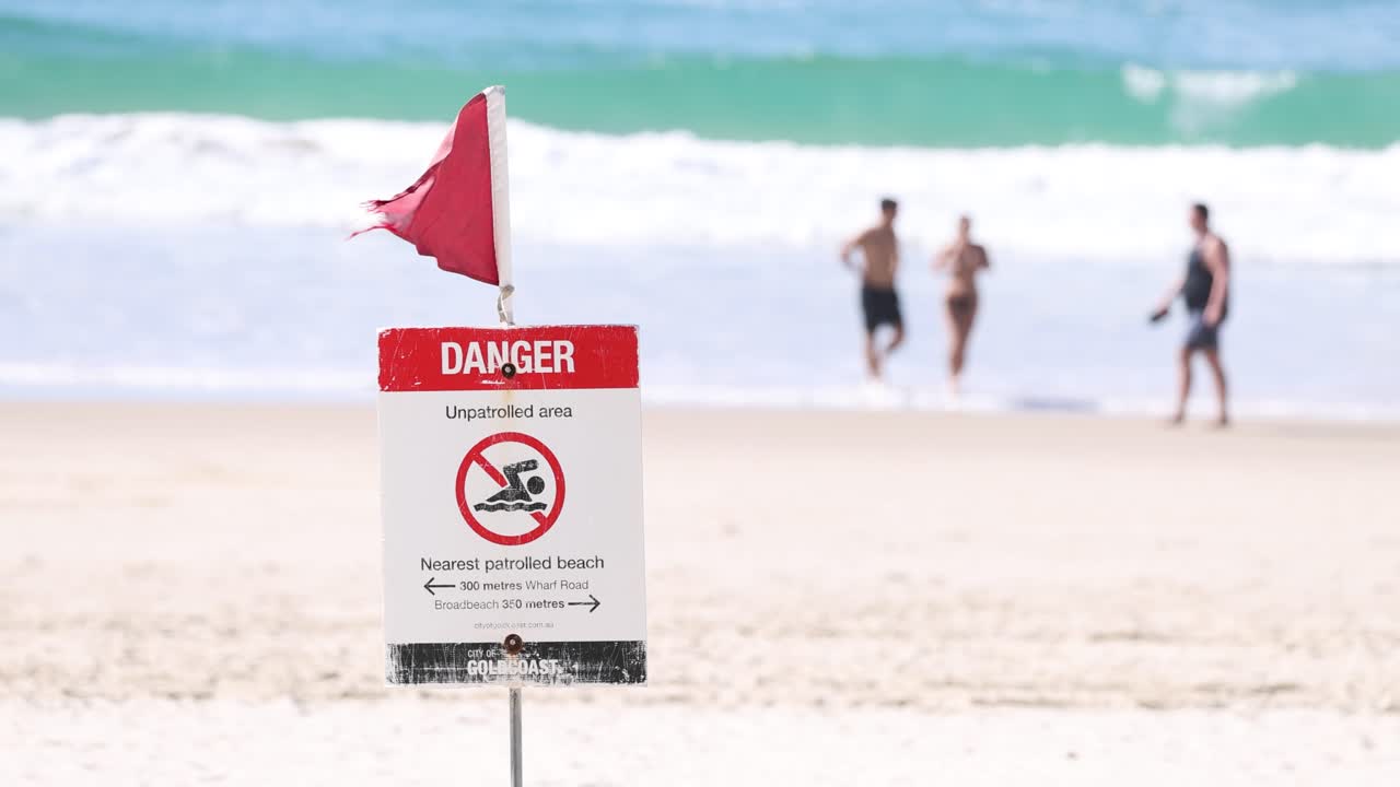 고 있는 사람 들 과 함께 해변 에 있는 경고 표지판