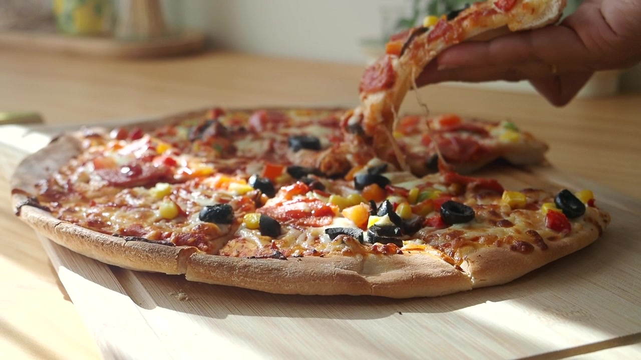 Mano che solleva una fetta di pizza calda e filante con salame piccante e olive