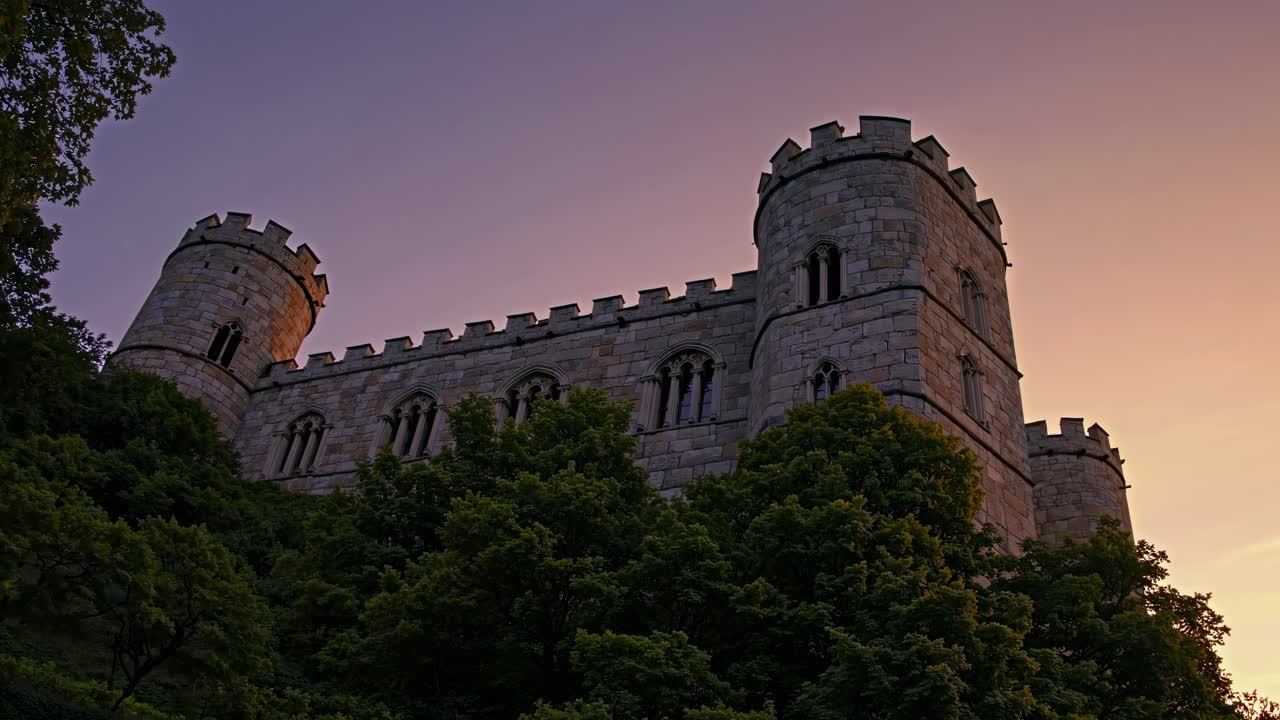 Majestic castle captured at sunset from a low-angle, highlighting its towers against a colorful sky