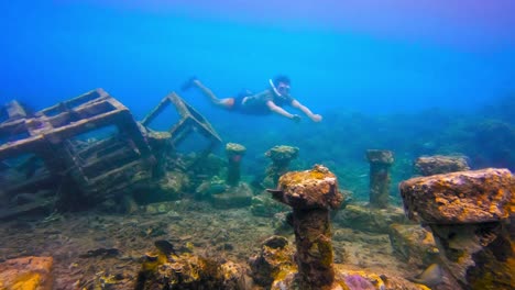 man snorkeling close to submerged garbage-like structure in the sea