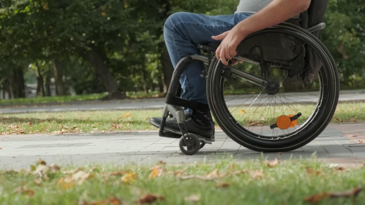 hombre feliz con discapacidad en silla de ruedas caminando por el callejón del parque