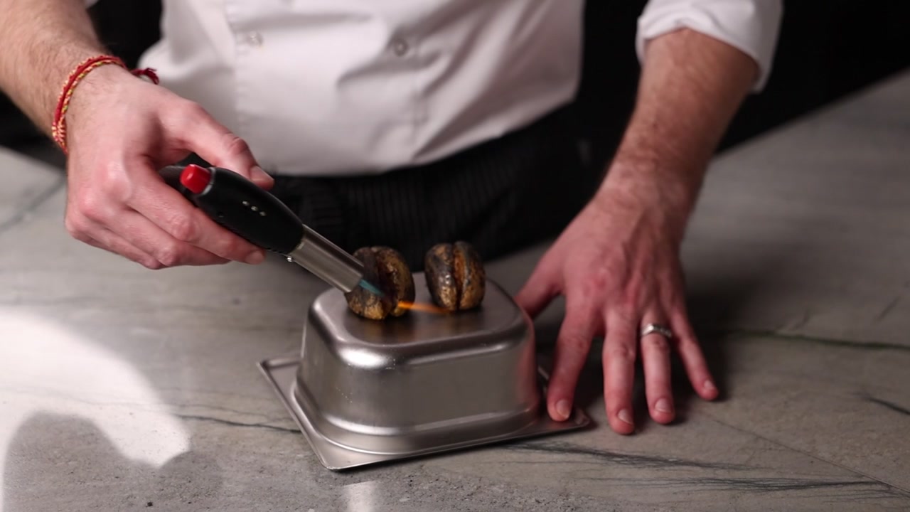 Chef che utilizza un cannello da cucina per scottare il cibo in una cucina professionale