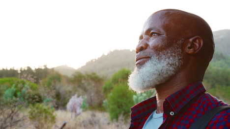 close up portrait of active senior man with backpack hiking in countryside