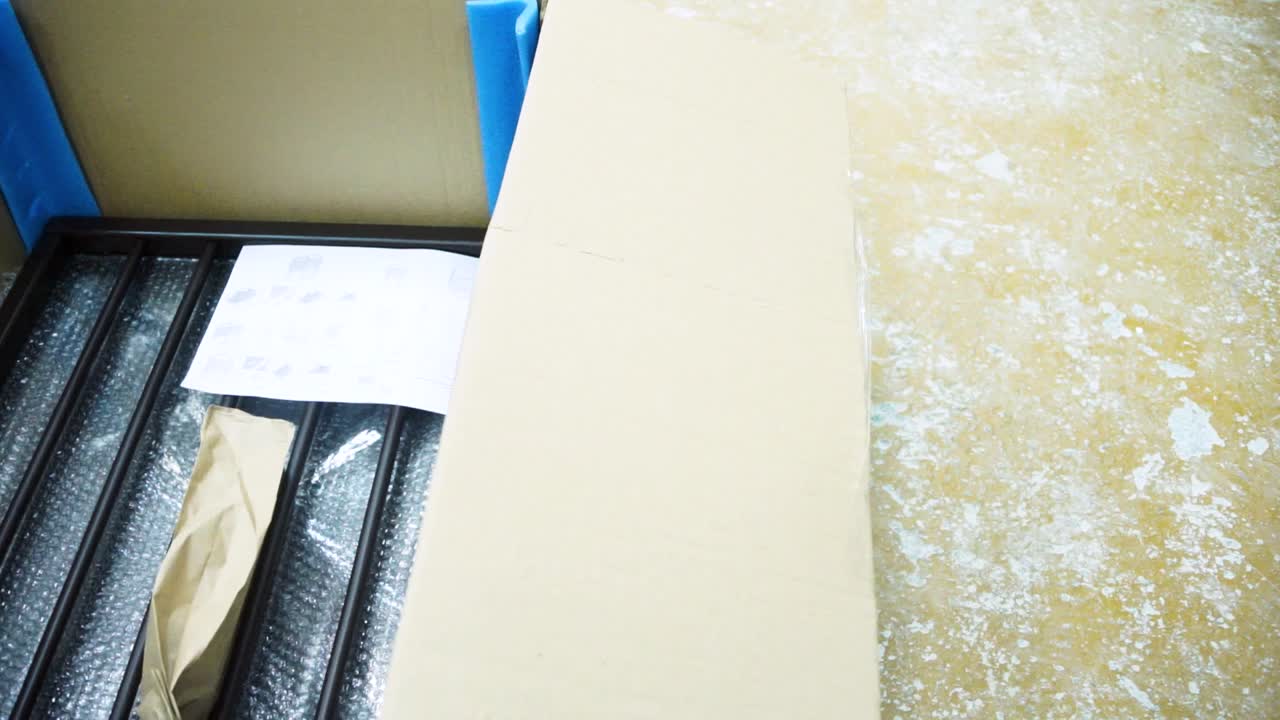 어두운 갈색의 금속 침대 프레임을 풀고 있습니다.