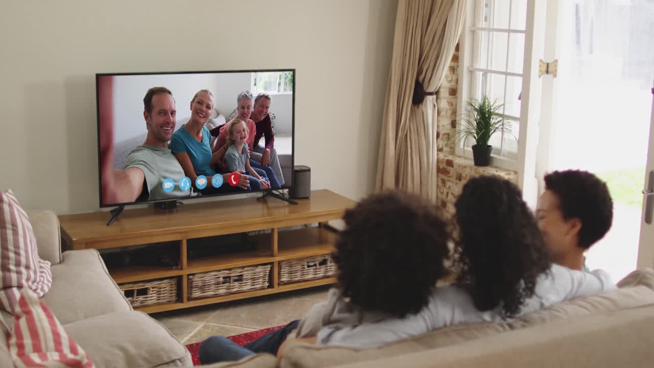 Famiglia afroamericana che fa una videochiamata in TV mentre è seduta sul divano a casa