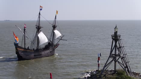 replica voc ship sail out of hoorn harbour past small lighthouse