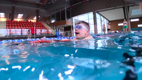 young active child swimming under water wearing goggles - float in public swimming pool