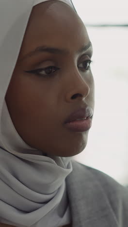 upset african-american woman with hijab sits in office center slow motion. muslim lady with depression disorder. negative emotions and mental state