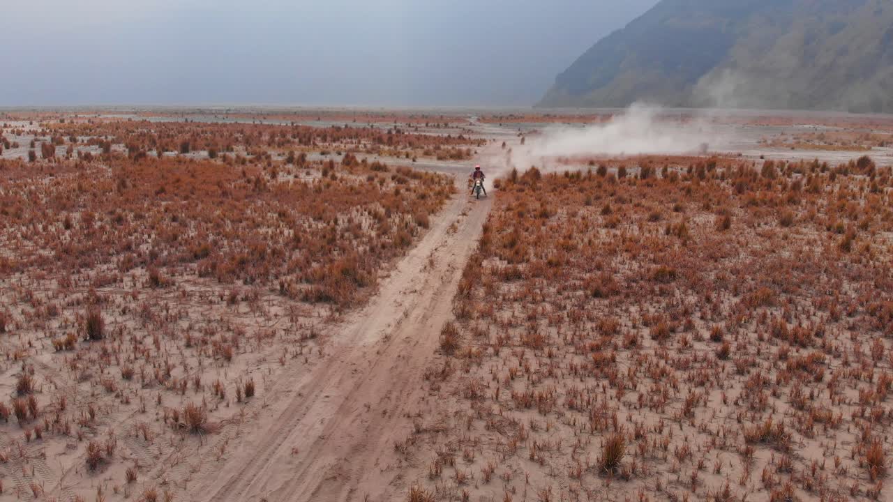 Motorcykel suser over Bromos sandede terræn ved solopgang. Indonesien, Østjava