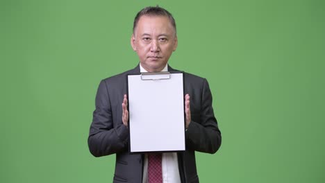 mature japanese businessman showing clipboard at camera