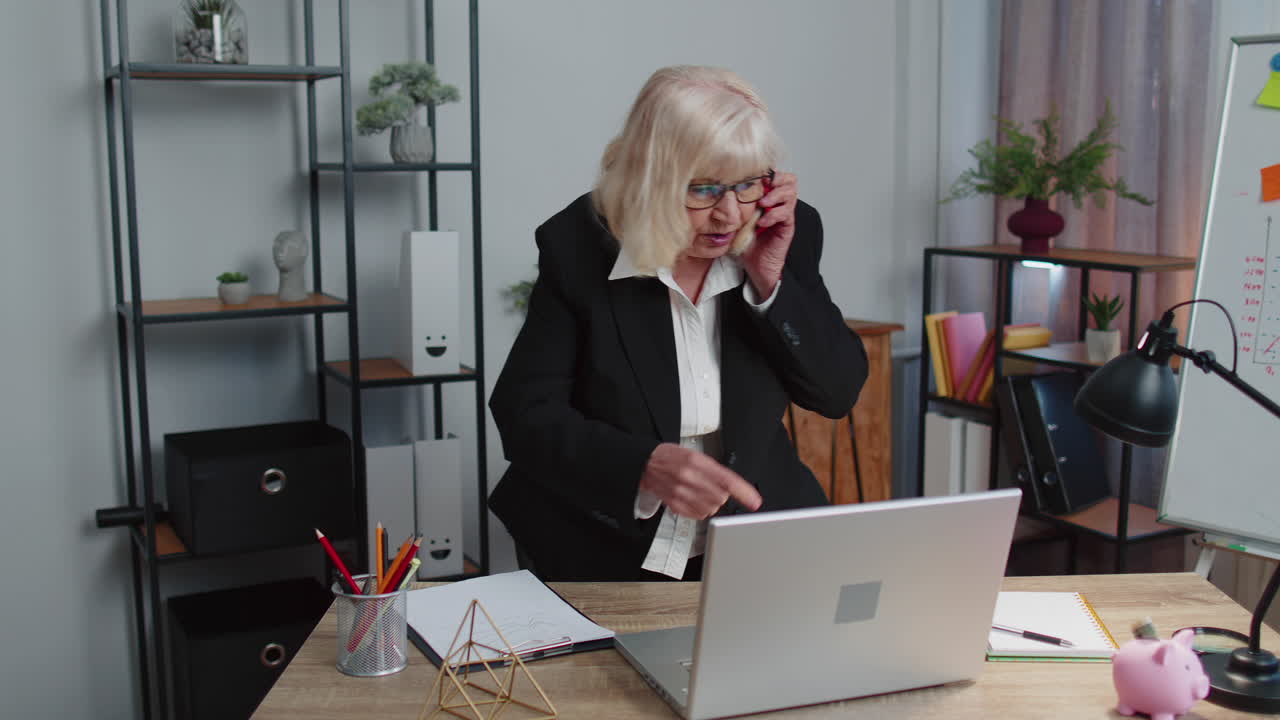 Angry senior business woman making phone call at office work annoyed boss talking mobile quarrel