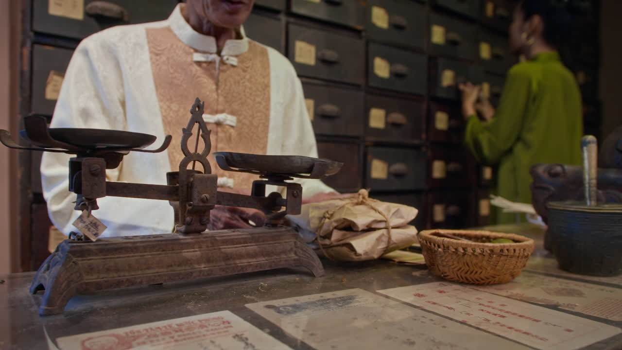 Man in Traditional Asian Clothes Measuring Herbs on Scale at Pharmacy