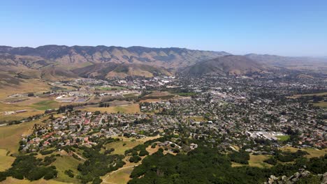 Drone-cresting-hill-to-reveal-beautiful-city-of-San-Luis-Obispo-and-surrounding-landscape