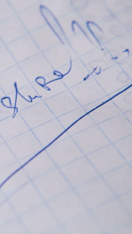 young man writes question are you sure with blue ball pen on blank checkered paper sheet extreme close view