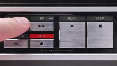 extreme close up of buttons on an old antique or vintage vcr pushing and holding on the rewind button