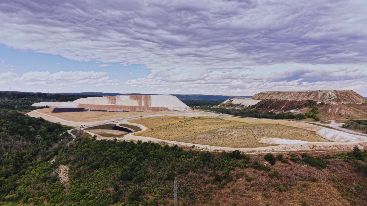 Aterro sanitário perto de floresta durante o dia com nuvens no céu.