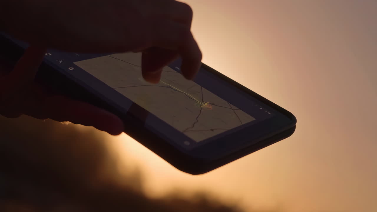 Person using a smartphone map app at sunset