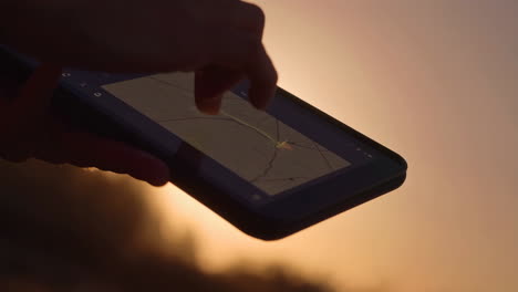 person using a smartphone map app at sunset
