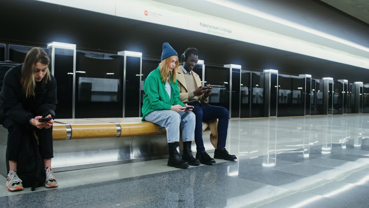 People waiting at a subway station while using technology