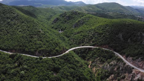 cars driving along a beautiful mountain pass with rolling, green hills in the background