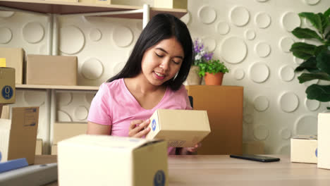 asian women business owner working at home with packing box on workplace