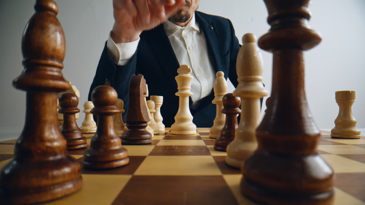 Unknown man playing chess logic board game closeup. Player hand moving figure
