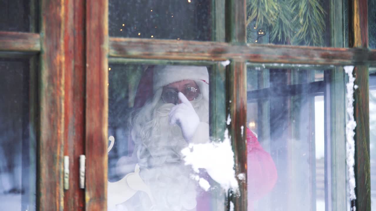 Santa Claus inside the house at window. Snowball is broken into the window and Santa quarrels showing hand gestures