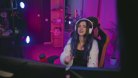 overhead view of young woman wearing headphones hitting desk in frustration while working in neon lit studio, facial expression revealing irritation and fatigue during intense creative session
