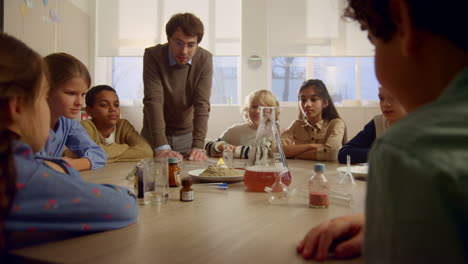 children studying chemistry at table. teacher doing pharaoh snake experiment