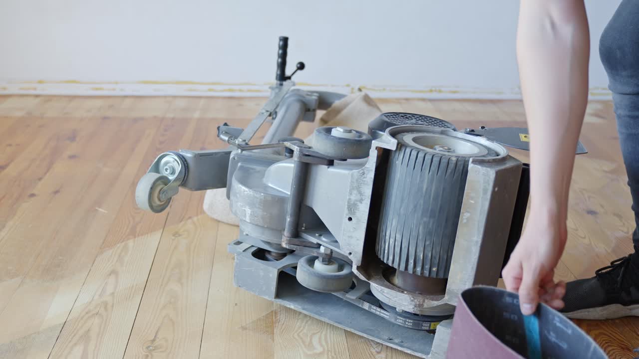 Person prepares industrial sanding machine to renovate home floor