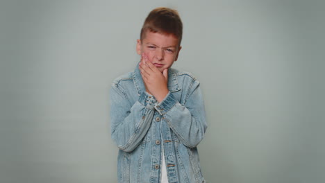 niño tocando la mejilla que sufre de dolor de dientes, caries o gingivitis esperando una cita con el dentista