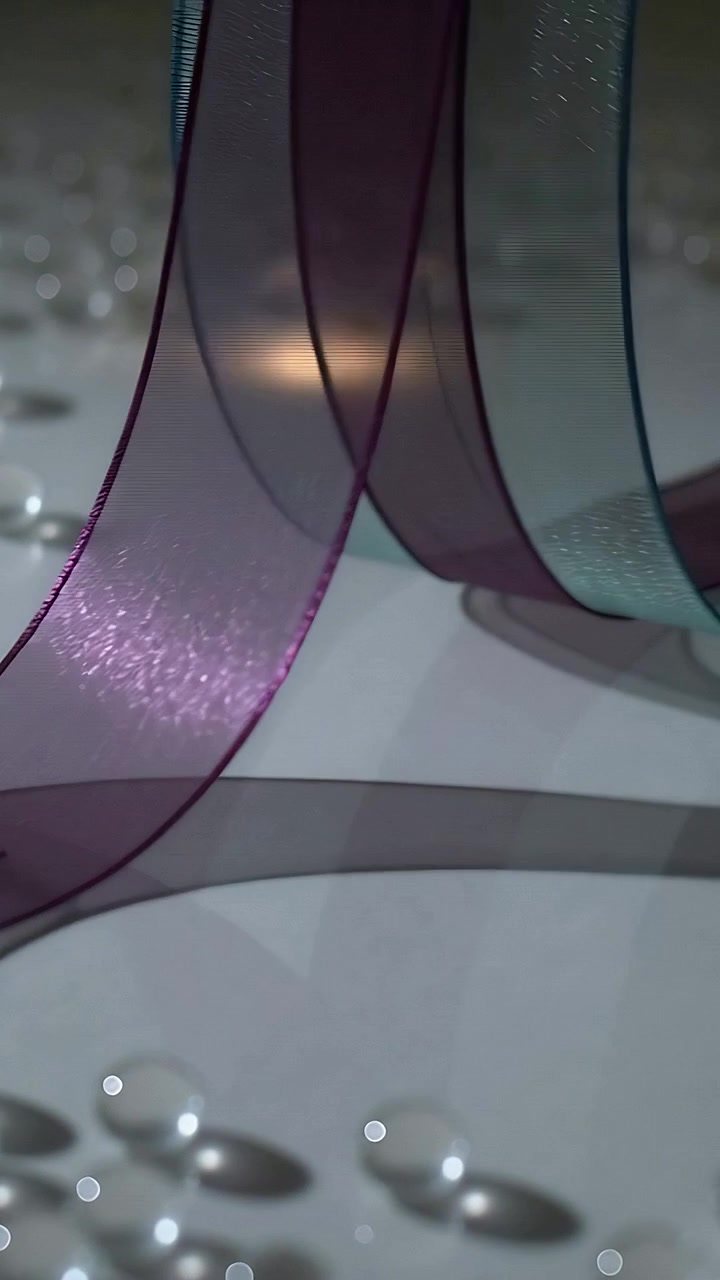 Vertical video: Camera pulling back, ribbon looping on white mat revealing purple, teal bands