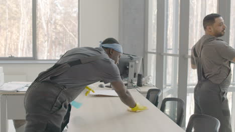 and arabic cleaning man cleaning the window panes and a desk inside an office 1