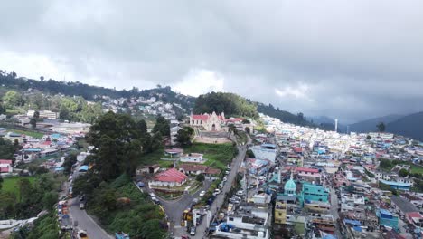 Drone-shot-of-Kodaikanal-town-and-Sacred-Heart-Catholic-Church-under-overcast-sky,-Dindigul,-Tamil-Nadu,-India