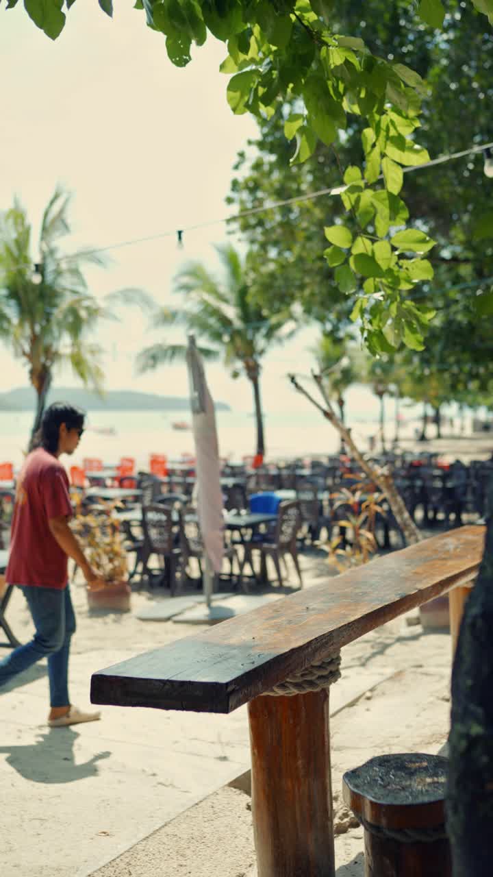 Vertical footage of chair arrangements of a restaurant on beach during daytime in Langkawi, Malaysia