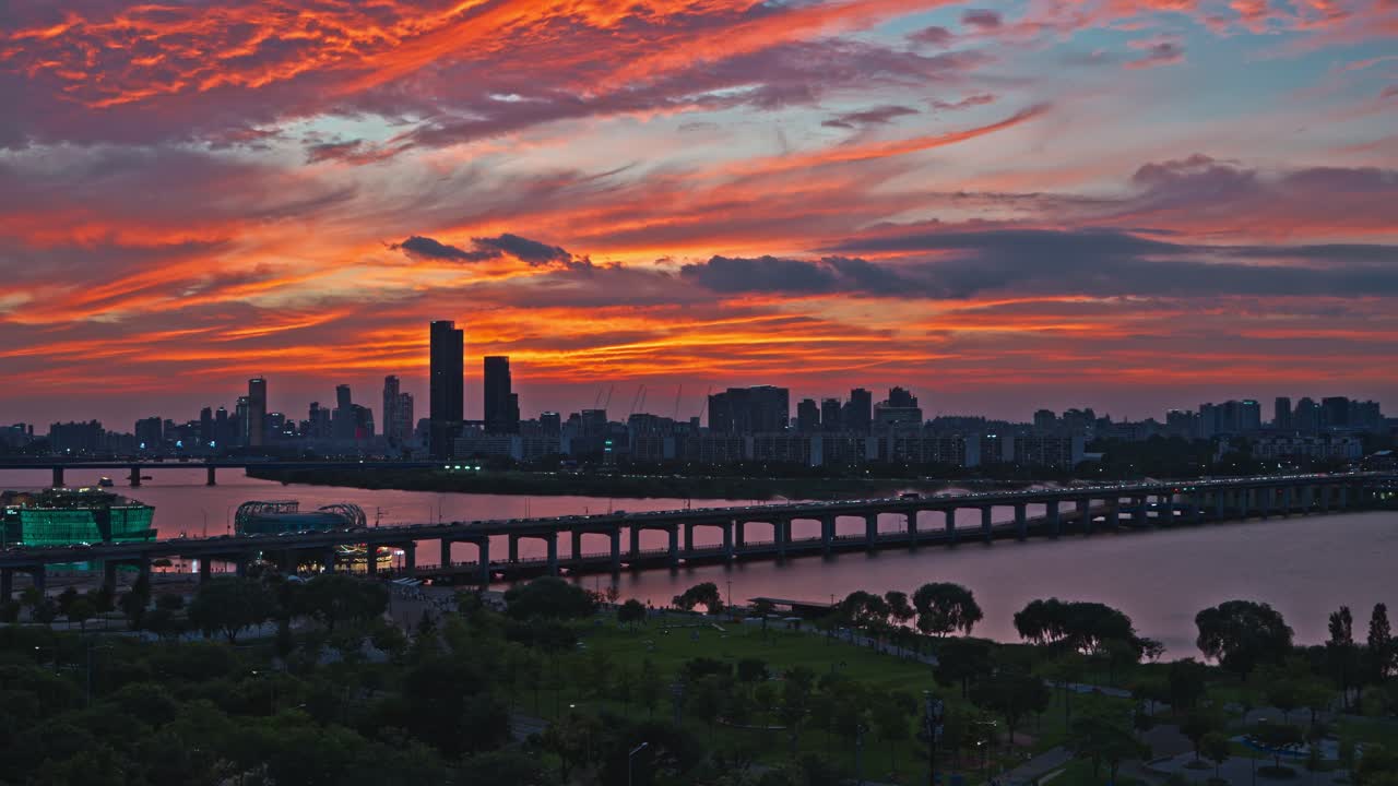 Stunning aerial view of Banpo Bridge, Hangang Park, Some Sevit islands with Seoul skyline at sunset under vivid orange, red and purple clouds filling evening sky and reflecting on Han River water