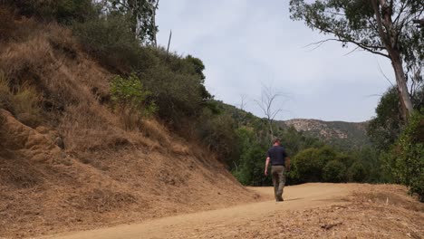 man hikes on dirt trail in griffith park, los angeles, california