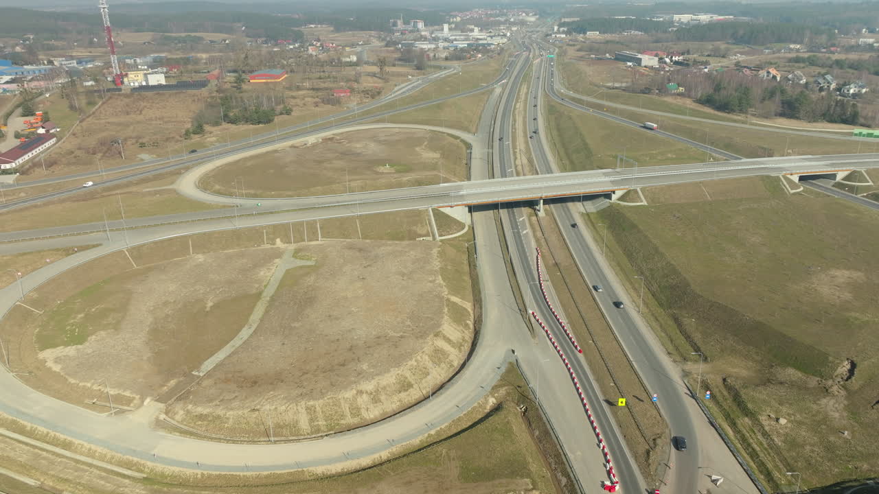 carreteras elevadas que se cruzan sobre terreno plano, con tráfico que circula en medio de áreas de construcción y desarrollo urbano cercano