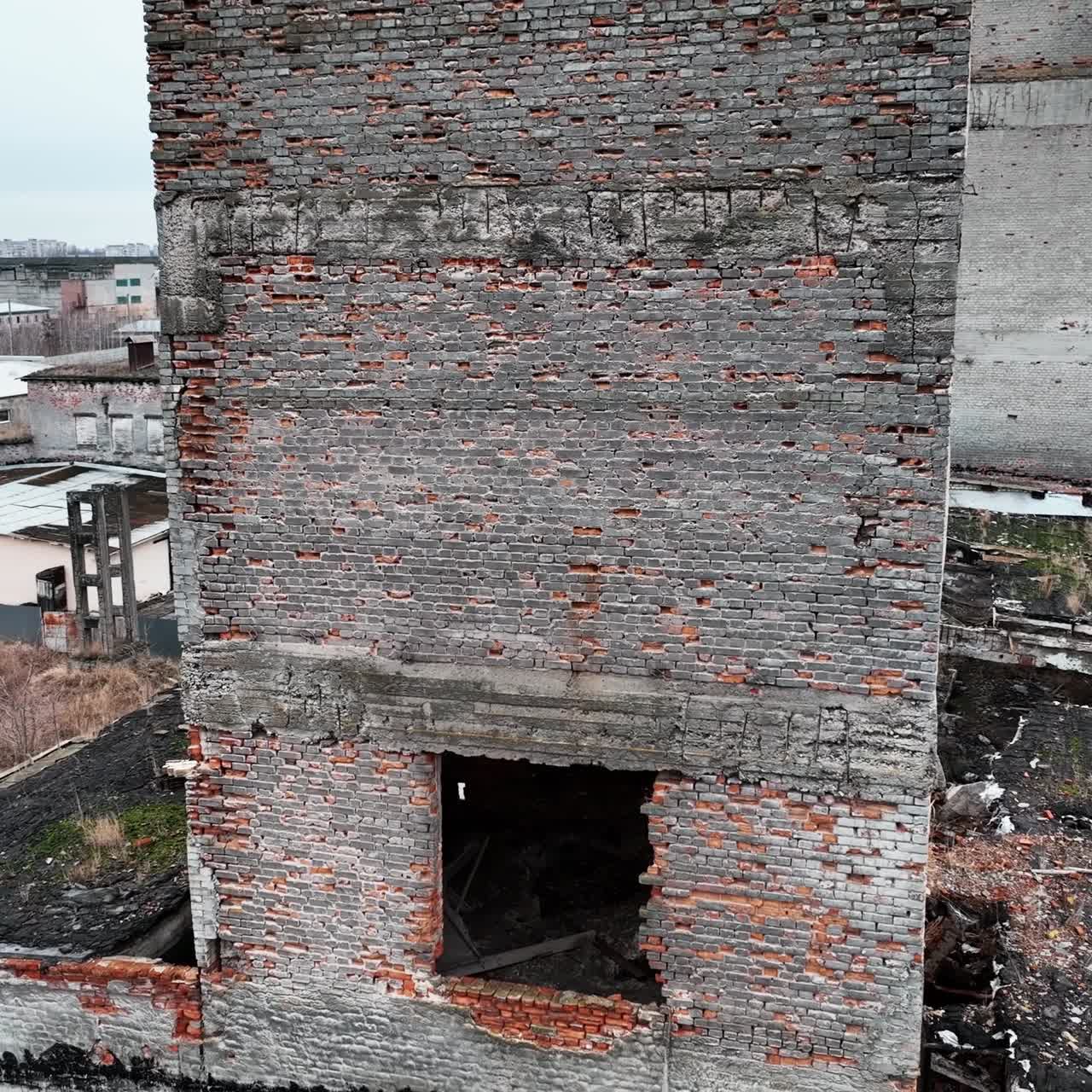 Bare brick walls and window holes in the bombed buildings. Ruined architecture resulting from air strike. Drone shot
