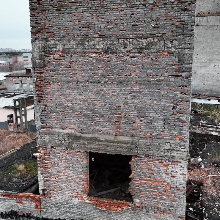 Paredes de tijolos aparentes e buracos de janelas em edifícios bombardeados. Arquitetura arruinada resultante de ataque aéreo. Imagem feita por drone